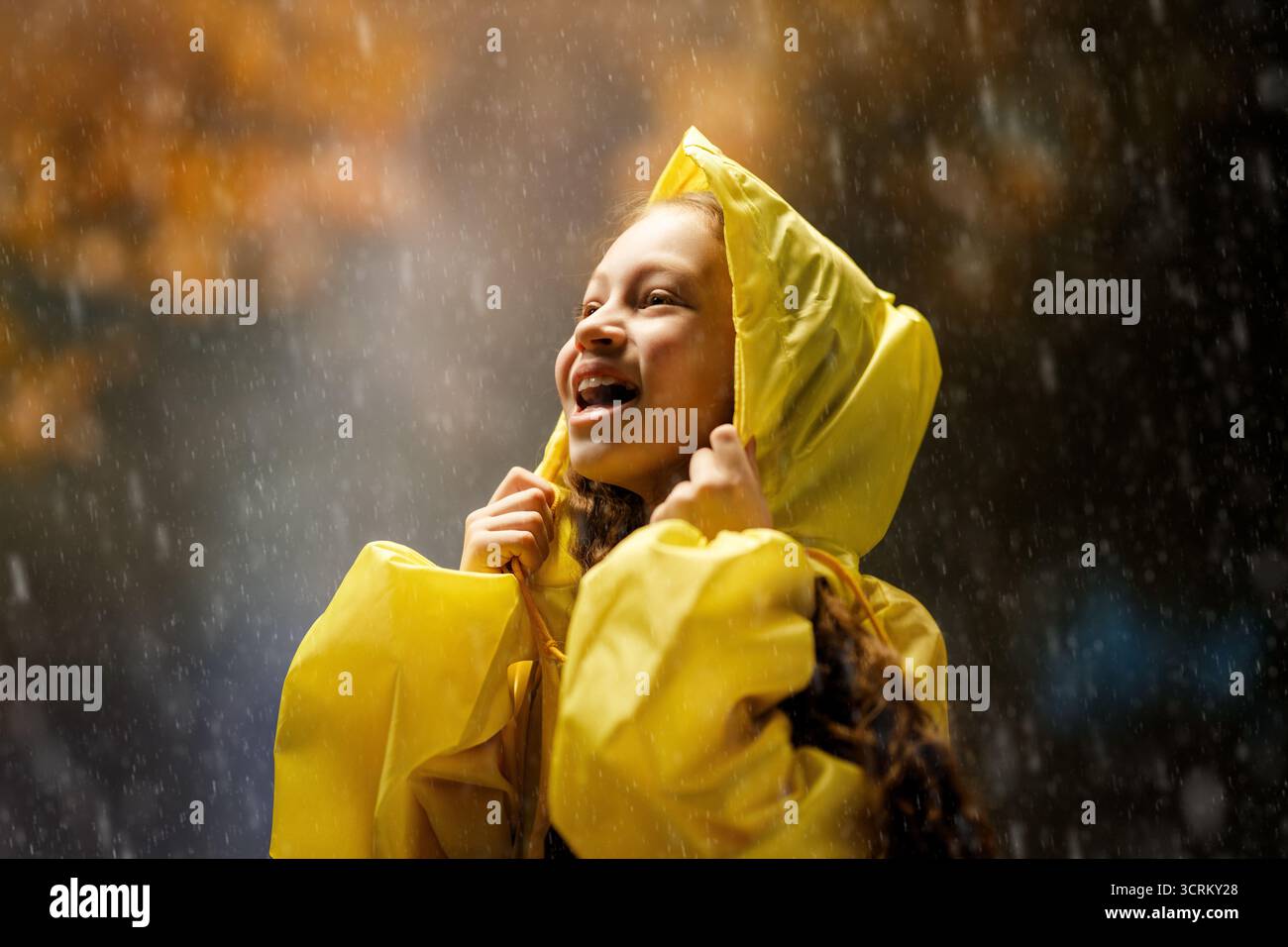 Glückliches kleines Mädchen im Regen auf einem Herbstspaziergang Stockfoto