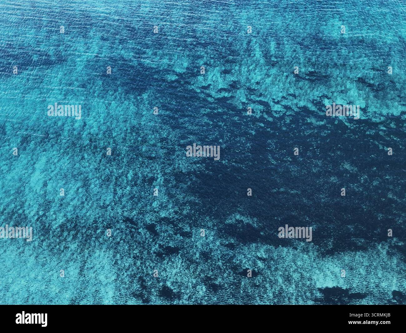 Aus der Vogelperspektive auf das türkisfarbene Meer im Kontrast zu den tiefblauen Tiefen, die komplizierte Muster auf dem Meeresboden enthüllen, Dugi Otok, Zadar County, Kroatien. Stockfoto