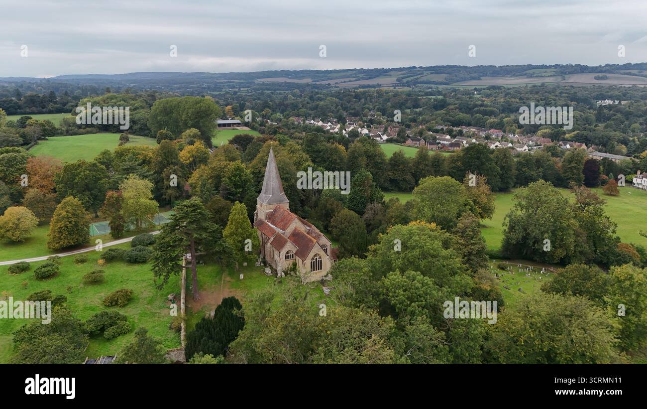 Blick aus der Vogelperspektive auf einen historischen Kirchturm, der die Skyline inmitten eines Meeres aus grünem Laub durchzieht, eingebettet in die sanften Hügel, Sevenoaks, England, Großbritannien. Stockfoto