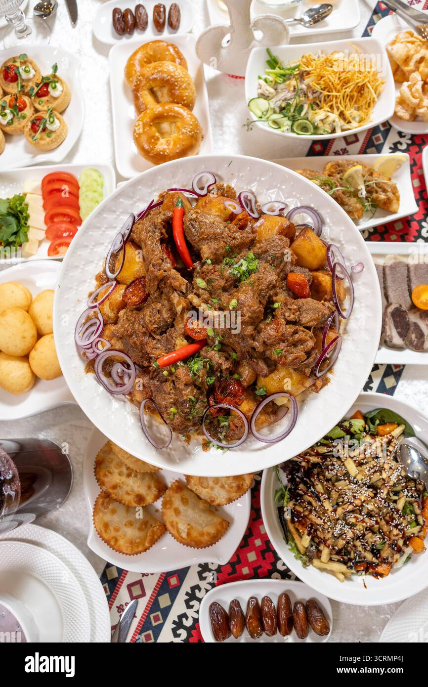 Blick von oben auf den Tisch mit Fleisch, Salaten und Desserts. Fängt den Geist der Großzügigkeit und Gastfreundschaft ein - perfekt für Catering-Kataloge und gehobene Restaurants Stockfoto