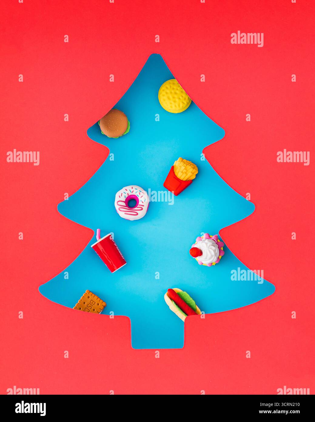 Winterkomposition mit Lebensmitteln, sichtbar durch eine weihnachtliche Lücke auf rosa Hintergrund. Weihnachtsessen und Neujahr. Stockfoto