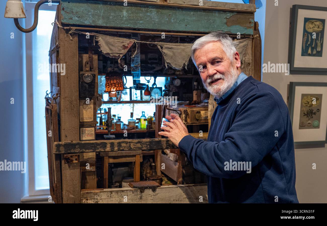 The Scottish Gallery, Edinburgh, Schottland, Vereinigtes Königreich, 02. Oktober 2025, 50 Jahre Naboland und die Familie Behrens: Reinhard Behrens hat in seinen Gemälden seit 50 Jahren in einer neuen Ausstellung ein alternatives Universum geschaffen, Naboland. Das mythische Land Naboland bietet U-Boot-Expeditionen, traumhafte Meereslandschaften und fantasievolle Kartographien. Im Bild: Reinhard Behrens mit einer von ihm geschaffenen Miniaturszene aus Naboland. Quelle: Sally Anderson/Alamy Live News Stockfoto