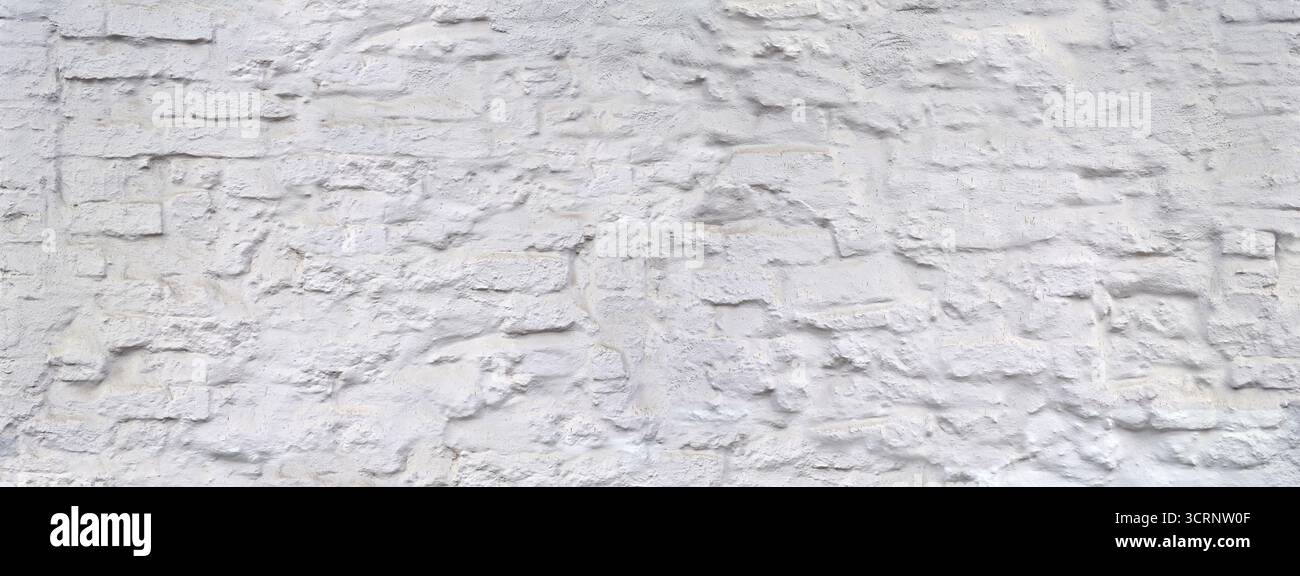 Raue, unebene, weiß lackierte Steinwand, schmutzig und mit Spritzern Stockfoto