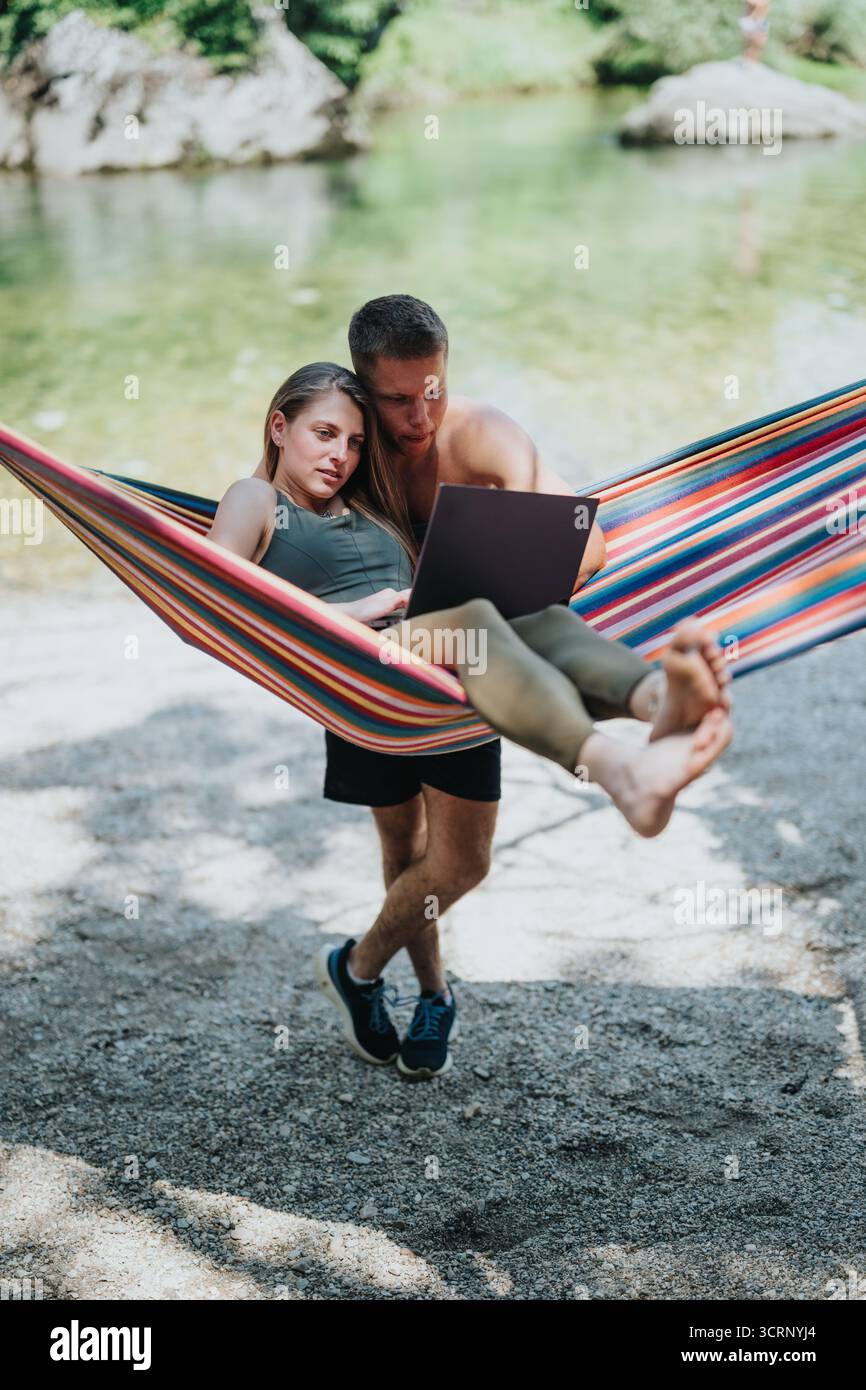 Ein Paar, das an einer Hängematte am See arbeitet Stockfoto