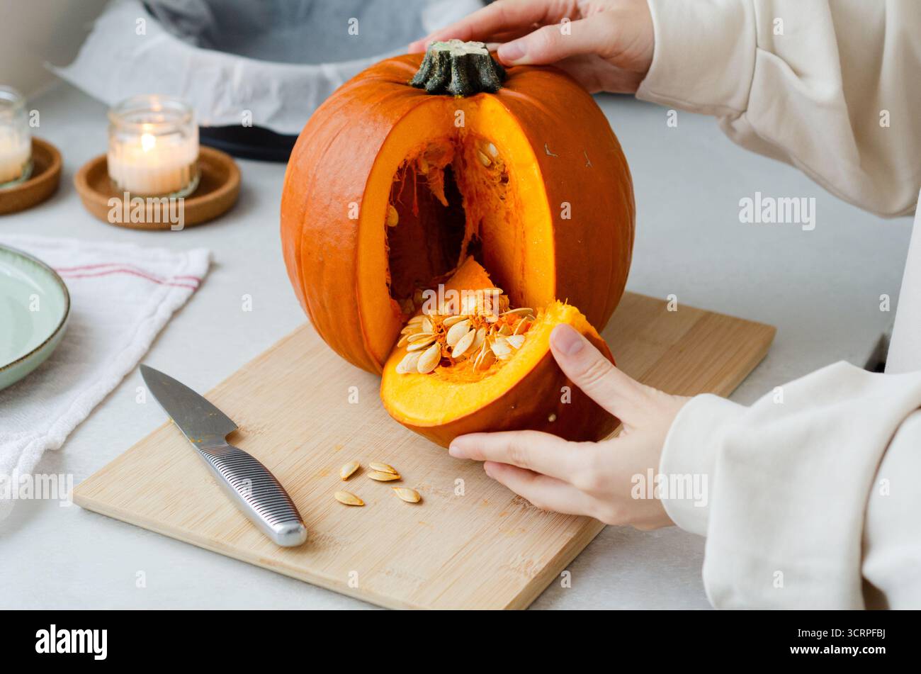 Frau, die geschnittenes Stück frischen Bio-Kürbis mit Samen zum Herbstkochen hält Stockfoto