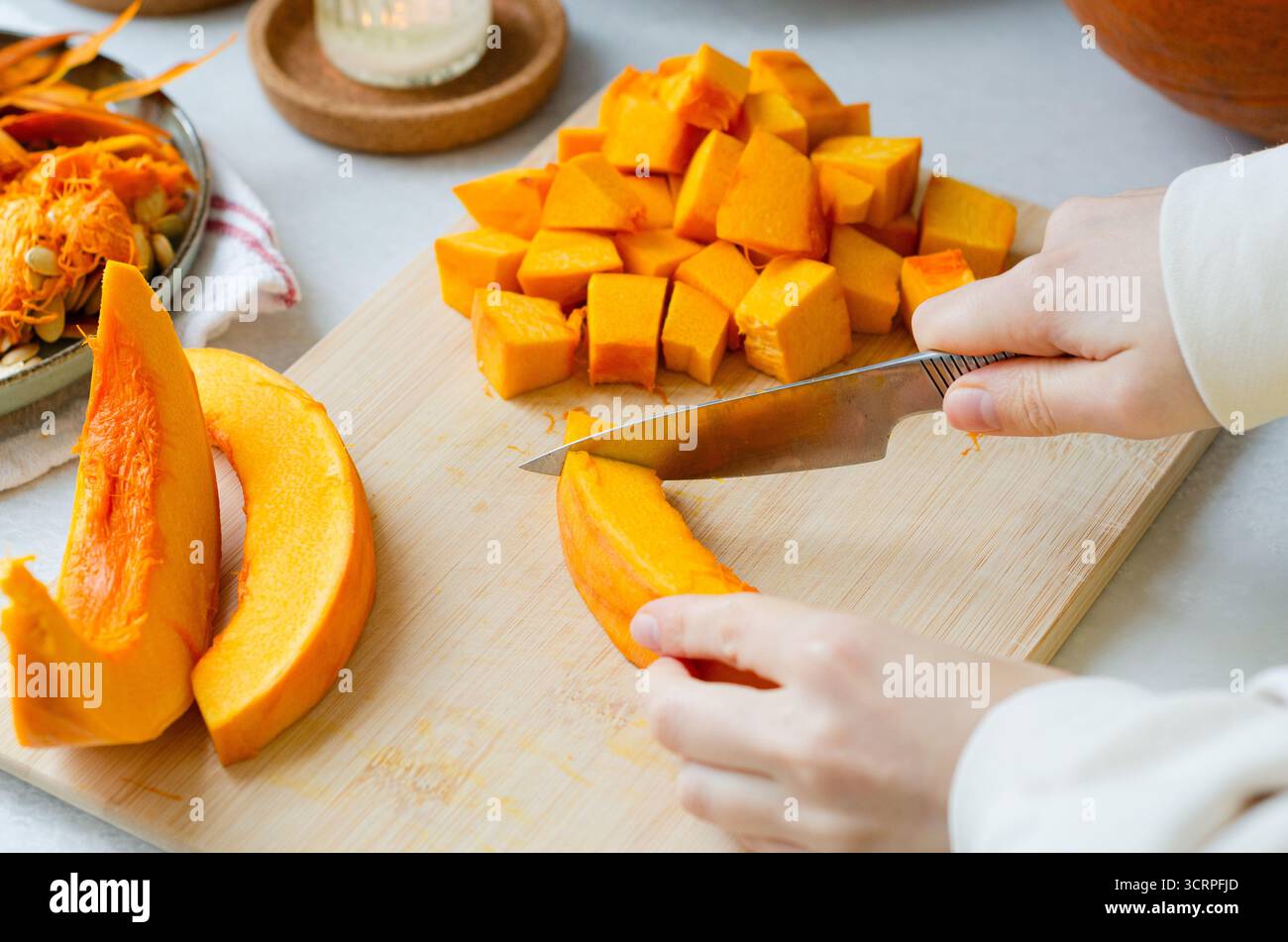 Nahaufnahme einer Frau, die Kürbis für Herbstrezepte in Würfel schneidet Stockfoto