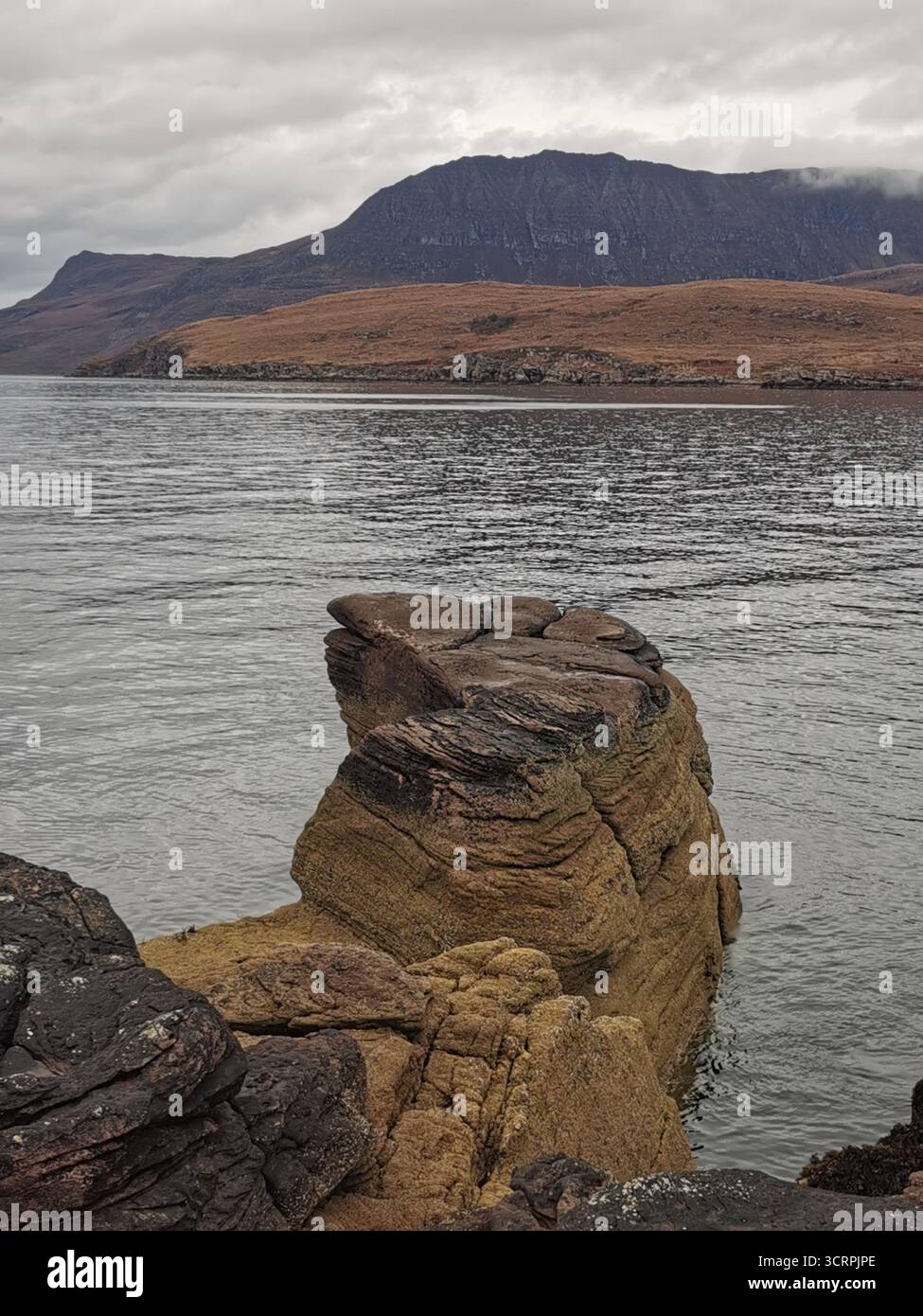 Giant’s Footprint Rock in der Nähe des Rhue Lighthouse, Ullapool. Eine natürliche Kuriosität, die in den Sandstein von Torridonian geschnitten wurde, und ein Anblick an der Nordküste 500. - Smartphone-aufgenommenes Stockfoto