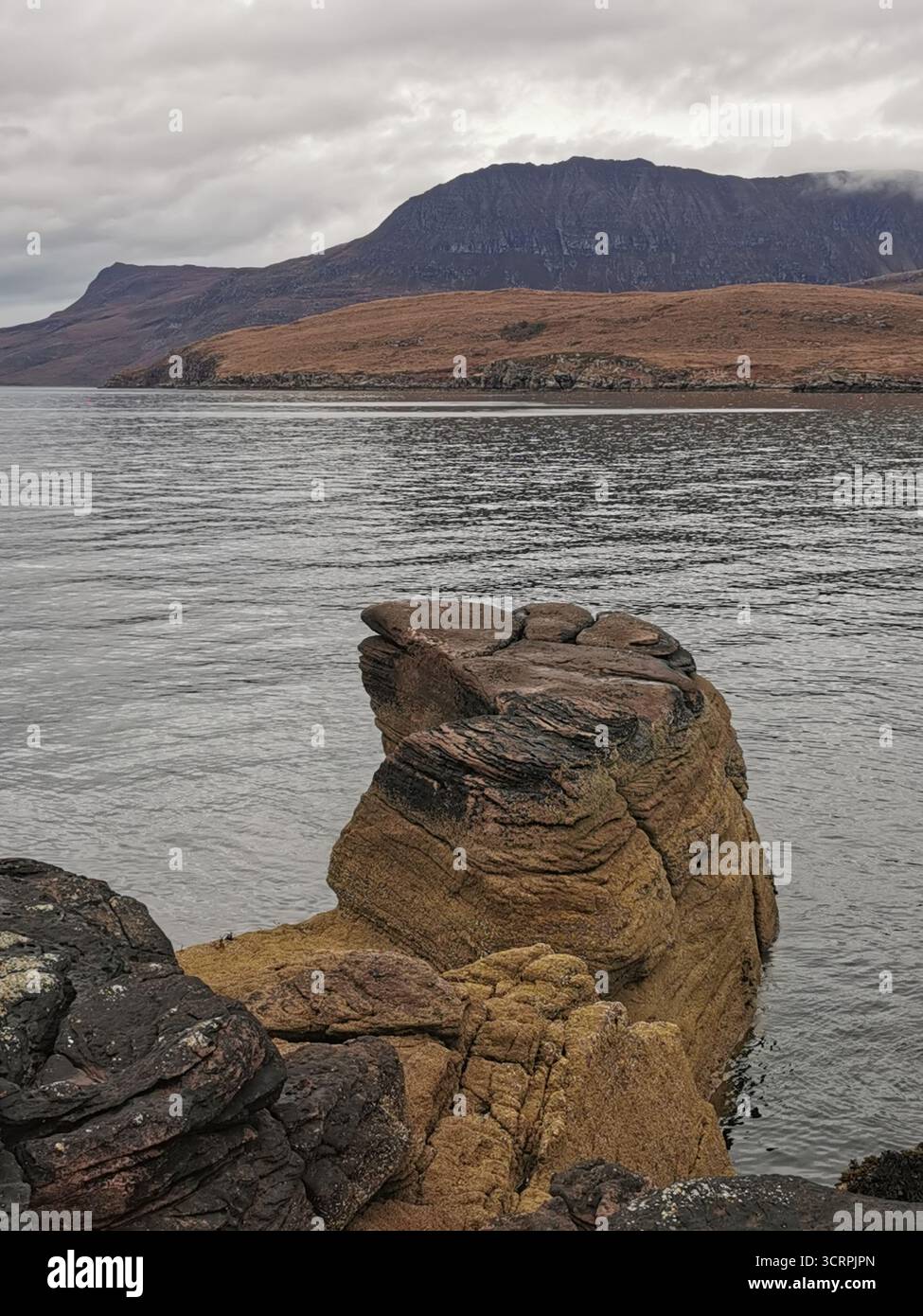 Giant’s Footprint Rock in der Nähe des Rhue Lighthouse, Ullapool. Eine natürliche Kuriosität, die in den Sandstein von Torridonian geschnitten wurde, und ein Anblick an der Nordküste 500. - Smartphone-aufgenommenes Stockfoto