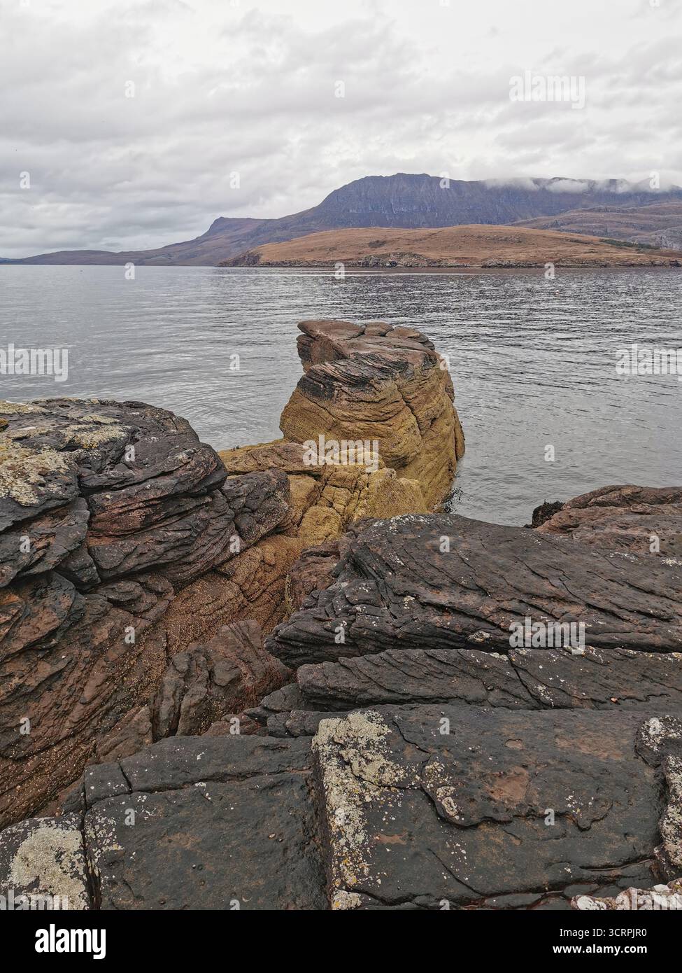 Giant’s Footprint Rock in der Nähe des Rhue Lighthouse, Ullapool. Eine natürliche Kuriosität, die in den Sandstein von Torridonian geschnitten wurde, und ein Anblick an der Nordküste 500. - Smartphone-aufgenommenes Stockfoto