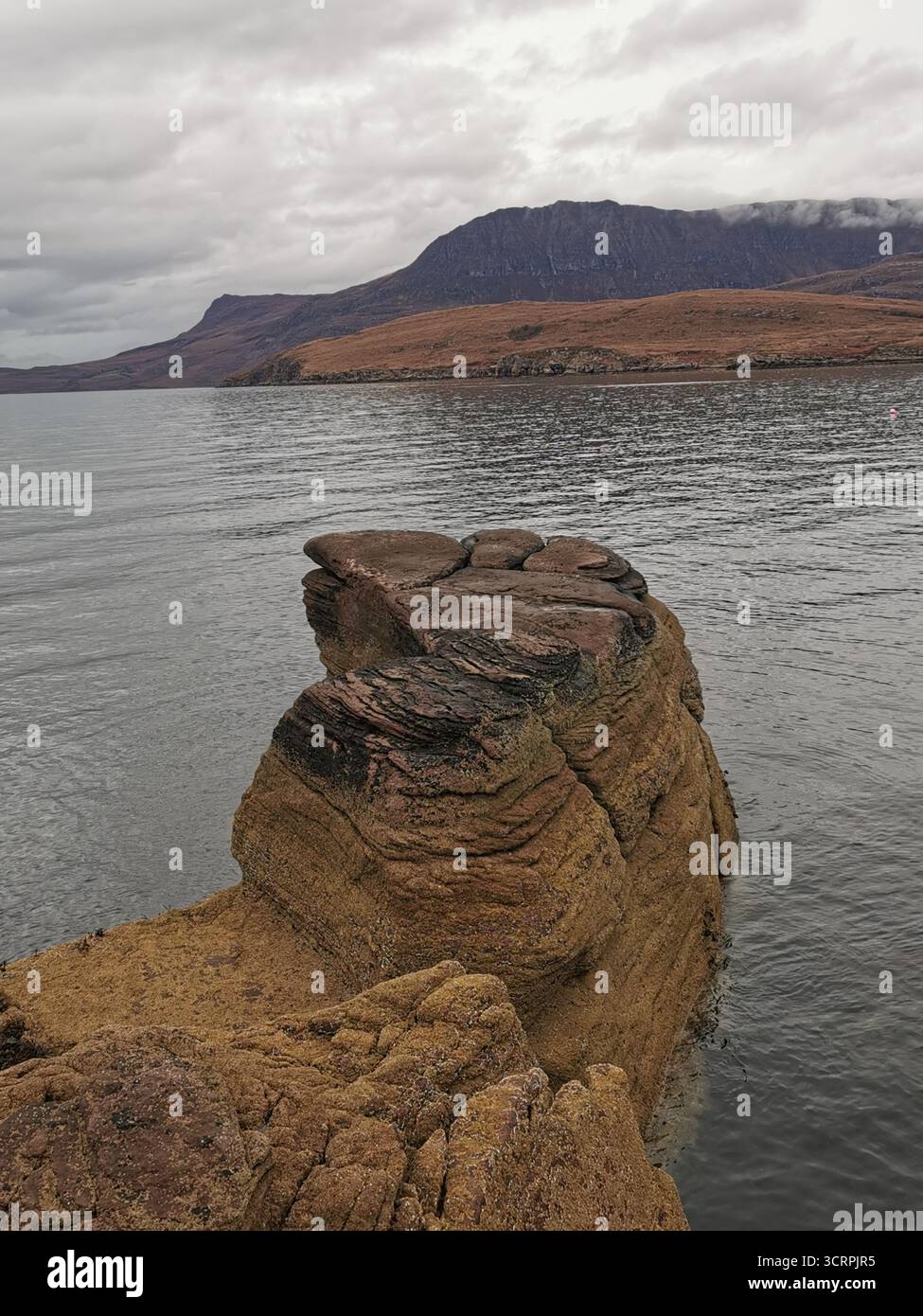 Giant’s Footprint Rock in der Nähe des Rhue Lighthouse, Ullapool. Eine natürliche Kuriosität, die in den Sandstein von Torridonian geschnitten wurde, und ein Anblick an der Nordküste 500. - Smartphone-aufgenommenes Stockfoto
