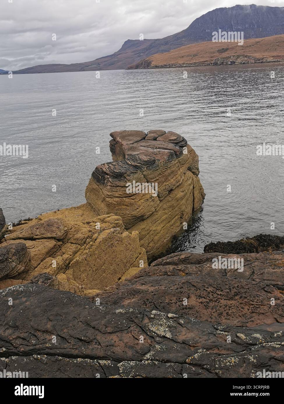 Giant’s Footprint Rock in der Nähe des Rhue Lighthouse, Ullapool. Eine natürliche Kuriosität, die in den Sandstein von Torridonian geschnitten wurde, und ein Anblick an der Nordküste 500. - Smartphone-aufgenommenes Stockfoto