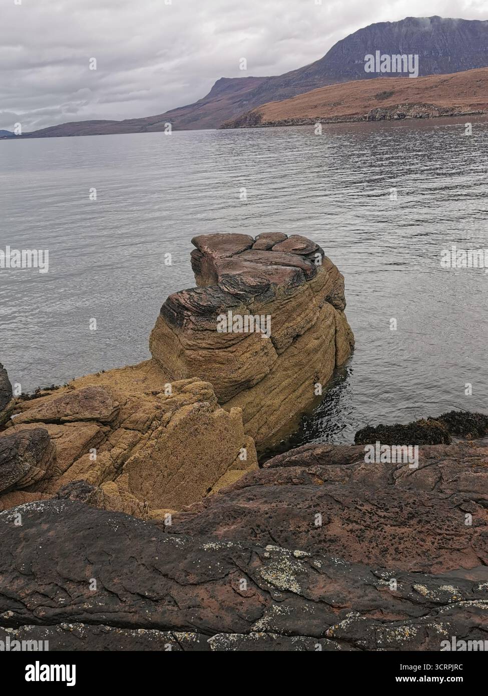 Giant’s Footprint Rock in der Nähe des Rhue Lighthouse, Ullapool. Eine natürliche Kuriosität, die in den Sandstein von Torridonian geschnitten wurde, und ein Anblick an der Nordküste 500. - Smartphone-aufgenommenes Stockfoto