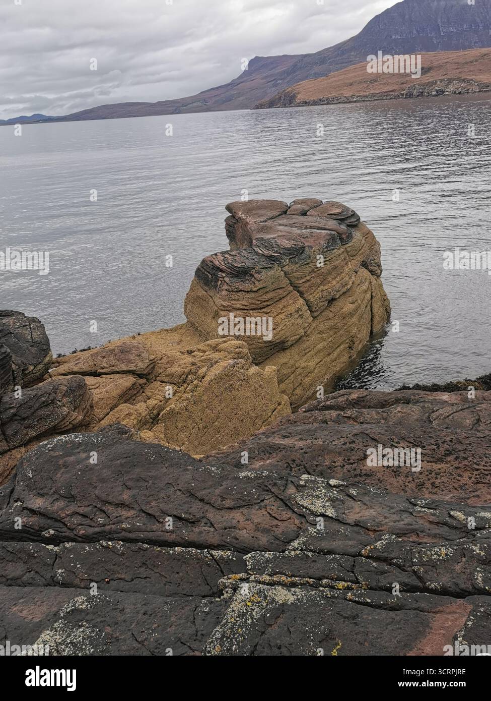 Giant’s Footprint Rock in der Nähe des Rhue Lighthouse, Ullapool. Eine natürliche Kuriosität, die in den Sandstein von Torridonian geschnitten wurde, und ein Anblick an der Nordküste 500. - Smartphone-aufgenommenes Stockfoto