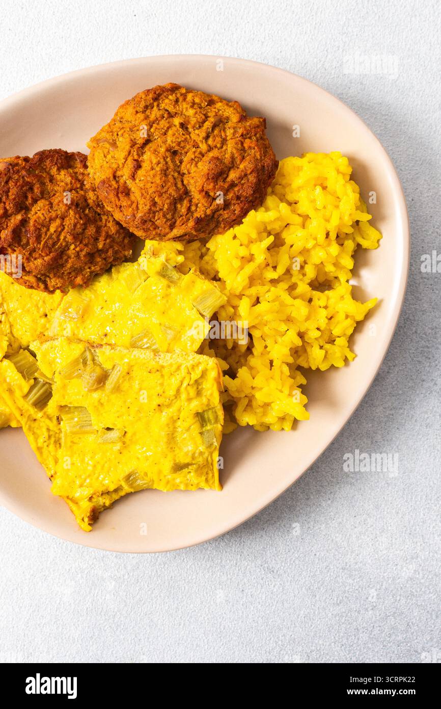 Ein lebhafter Teller mit flauschigem gelbem Reis, cremigen Rhabarber-Spiegeleiern und knusprigen Fleischgerichten bietet eine herzhafte und geschmackvolle Mahlzeit, die perfekt für einen ist Stockfoto