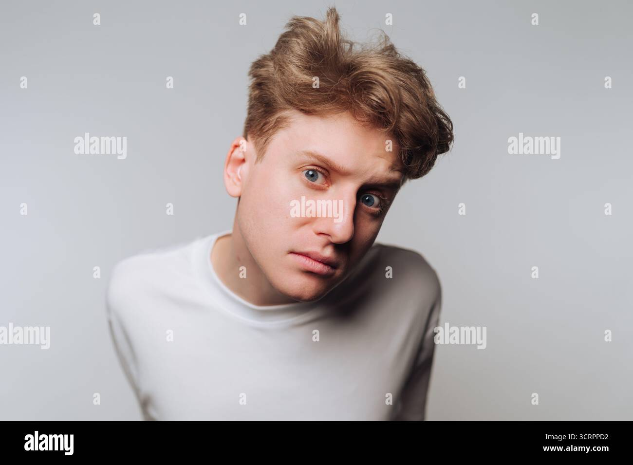 Junger Mann mit neugierigem Ausdruck, nach vorne geneigt. Stockfoto