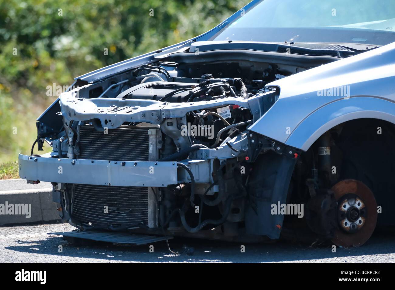 Beschädigtes Fahrzeug ohne vorderen Stoßfänger und Vorderrad, das nach einem Unfall oder einem mechanischen Defekt auf der Straße geparkt wurde. Stockfoto