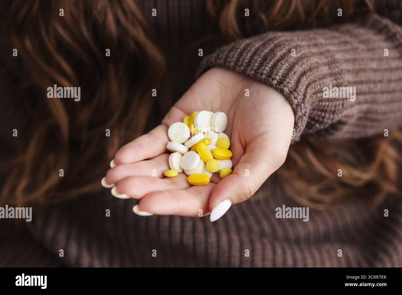 Frau, die Pillen in offener Hand hält. Medikamenteneinnahme und Gesundheitskonzept. Tägliche Behandlungsroutine und Gesundheitsunterstützung in Innenräumen. Stockfoto