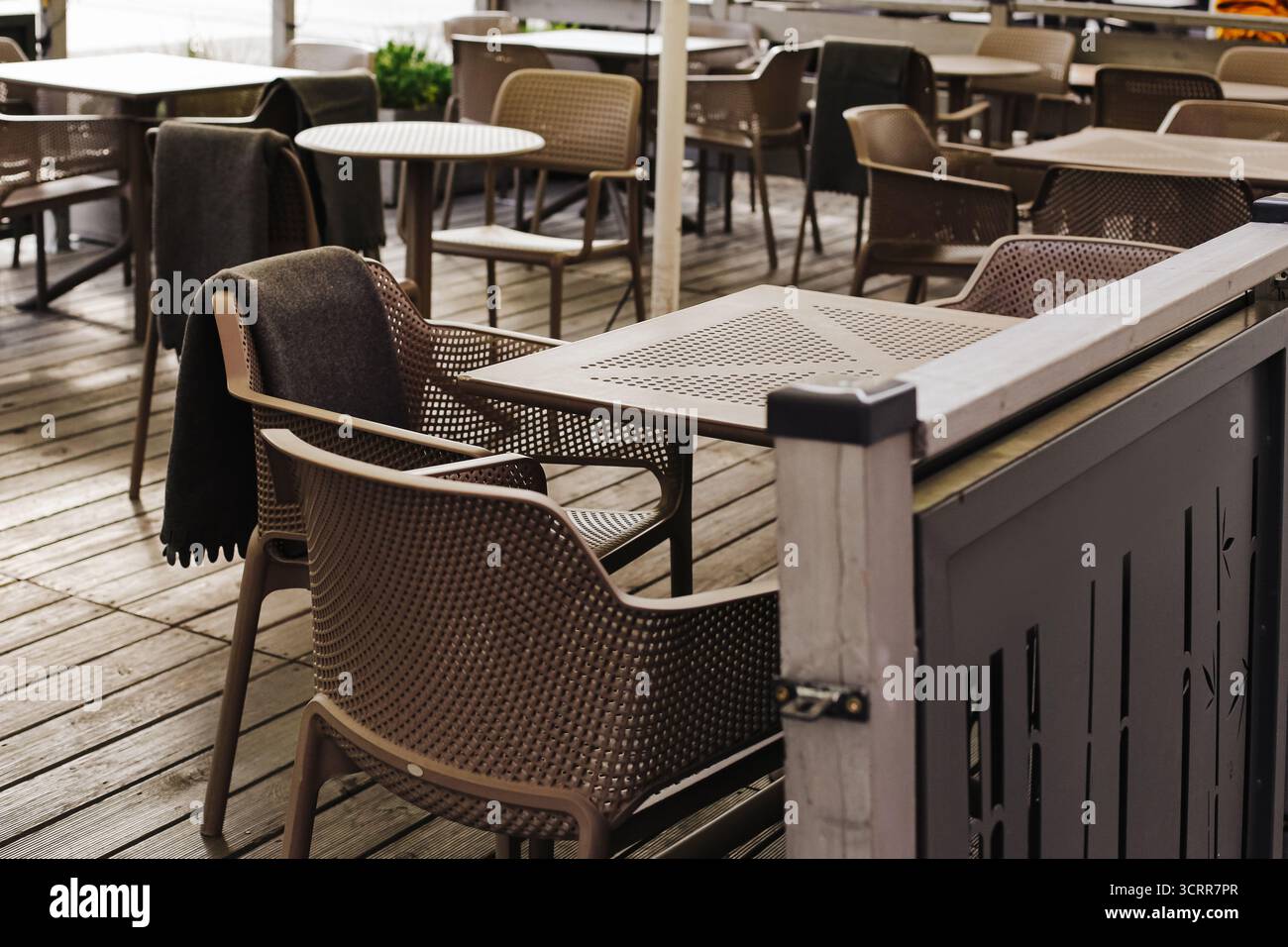 Terrasse im Freien mit leeren Stühlen und Tischen. Sonnige Tagesatmosphäre auf der Terrasse des Restaurants. Entspannende Freizeit und geselliger Lebensstil. Stockfoto