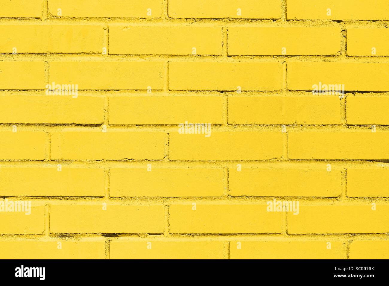 Gelber Backsteinmauerhintergrund. Hell lackiertes Mauerwerk mit geometrischem Konstruktionsmuster und urbanen architektonischen Details. Stockfoto