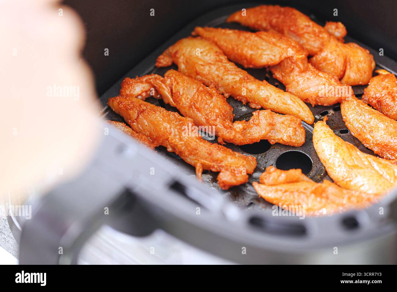 Rohes mariniertes Hähnchenfilet in einem Korb der Fritteuse. Zubereitung von frischem Geflügelfleisch für gesundes Kochen zu Hause. Küchengerät und Diät. Stockfoto