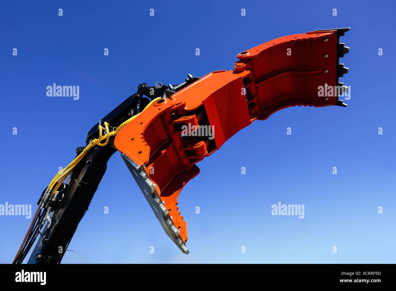Moderner Kranarm mit offenem Greifer, industrieller Greifer auf blauem Himmel Hintergrund. Stockfoto