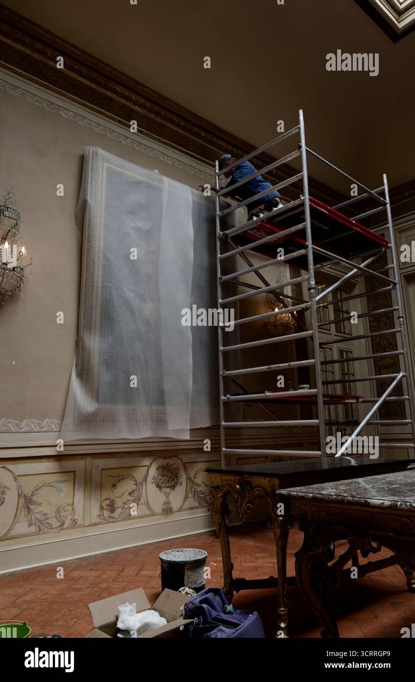 Ein Konservator arbeitet auf einem Gerüst, um ein großes Wandgemälde im kunstvollen Queluz-Palast zu restaurieren Stockfoto