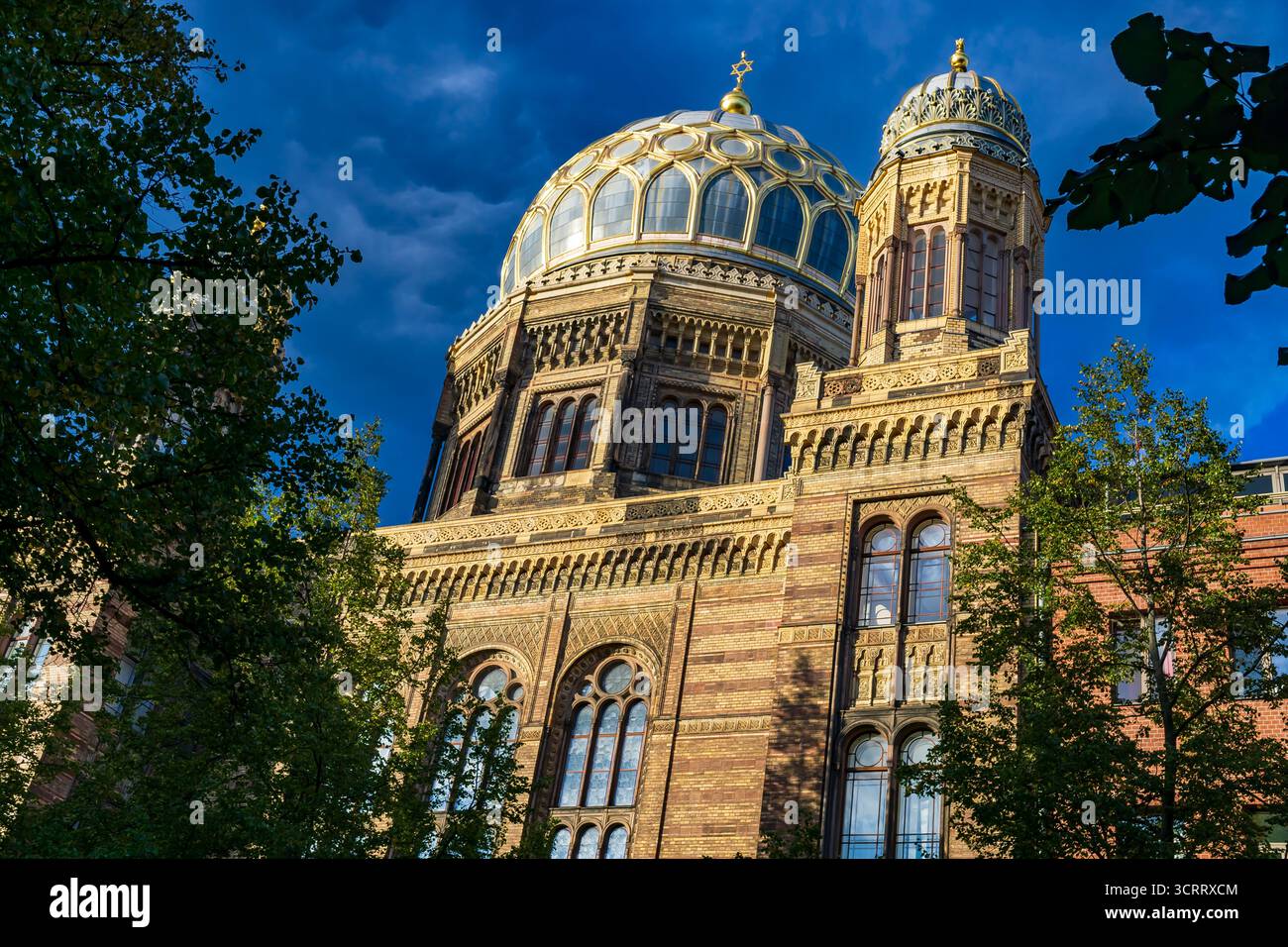 Goldene Kuppel und verzierte Fassade der Neuen Synagoge in Berlin, die in warmer Abendsonne mit tiefblauem Himmel leuchtet. Stockfoto