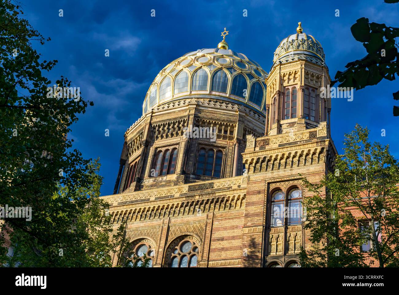 Goldene Kuppel und verzierte Fassade der Neuen Synagoge in Berlin, die in warmer Abendsonne mit tiefblauem Himmel leuchtet. Stockfoto