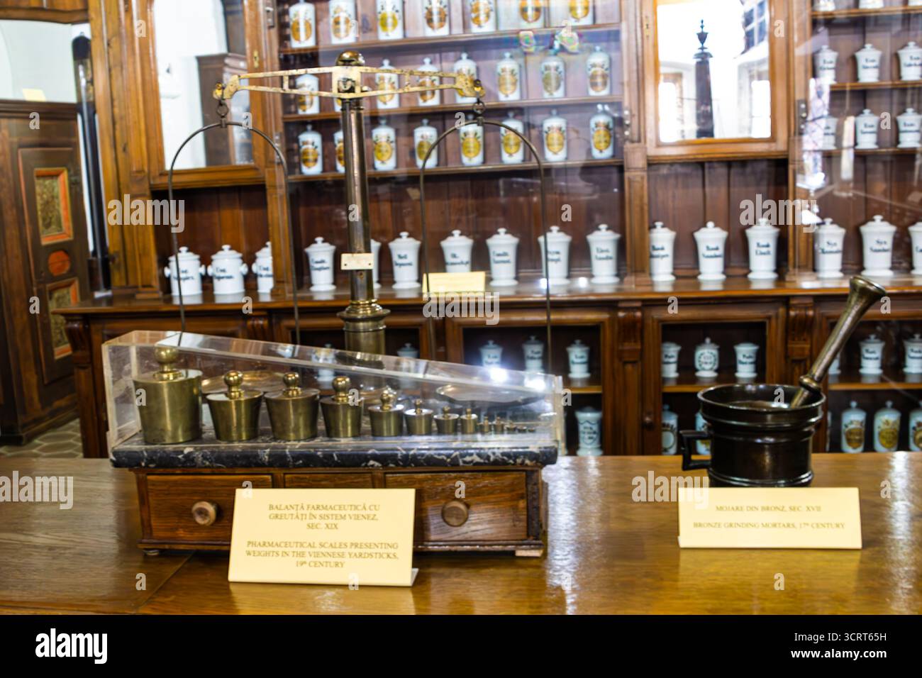 Pharmazeutische Waage mit Gewichten aus dem 19. Jahrhundert und Bronzemörtel und -Pissel aus dem 17. Jahrhundert im Apothekenmuseum in Sibiu, R. Stockfoto