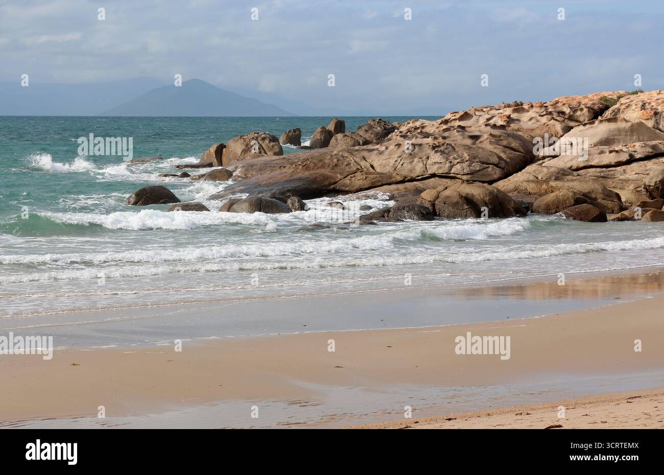 Sanfte Meereswellen, die an zerklüfteten Felsformationen am Rose Bay Beach in der Nähe von Bowen in Queensland, Australien, herumplätschern Stockfoto