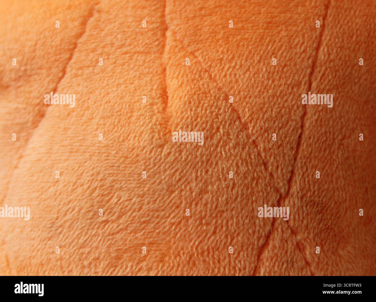 Nahaufnahme strukturierter abstrakter Hintergrund aus orangefarbenem Plüschstoff Stockfoto