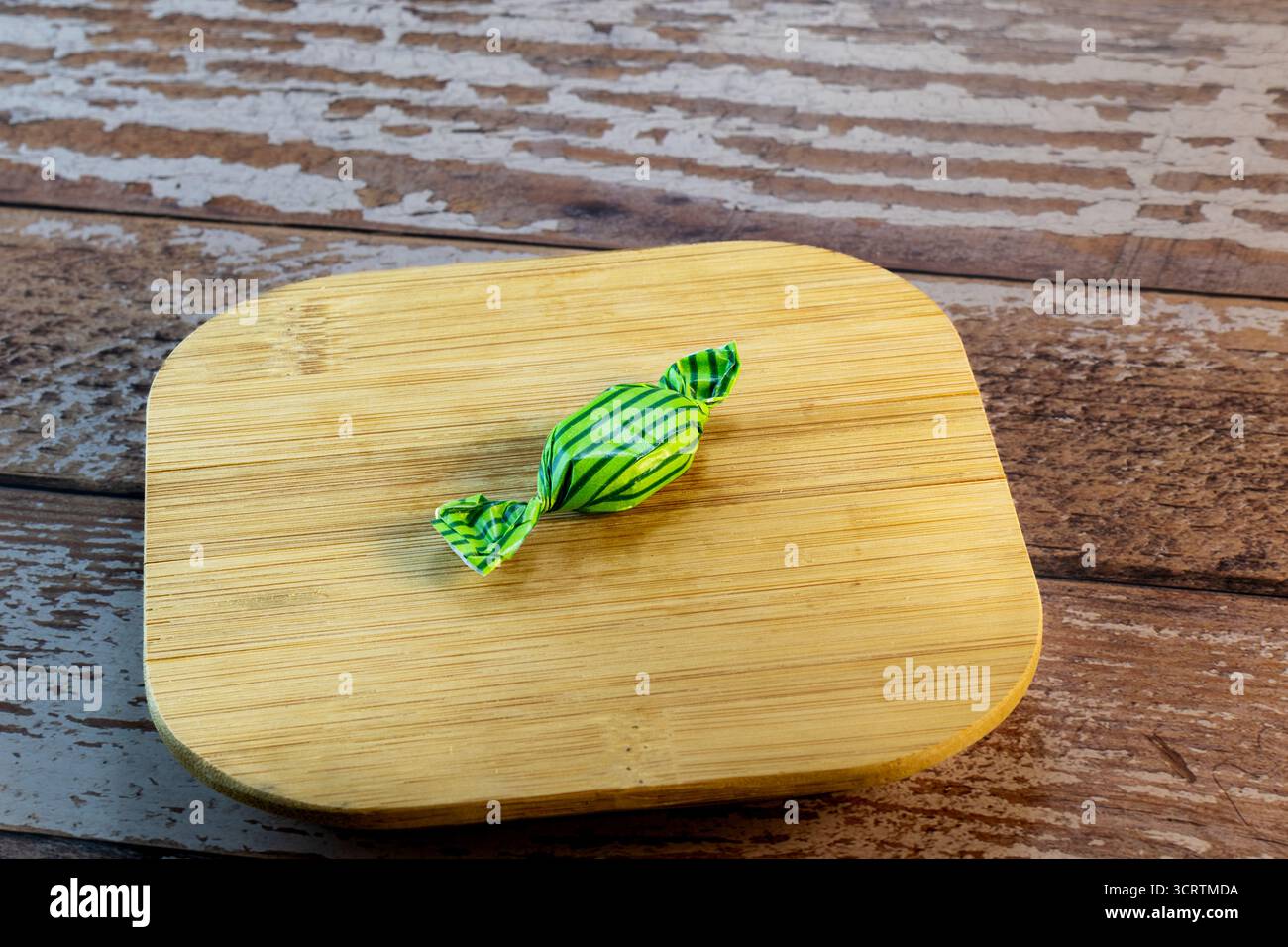 Eingewickelte Süßigkeiten auf rustikalem Holzbrett Stockfoto