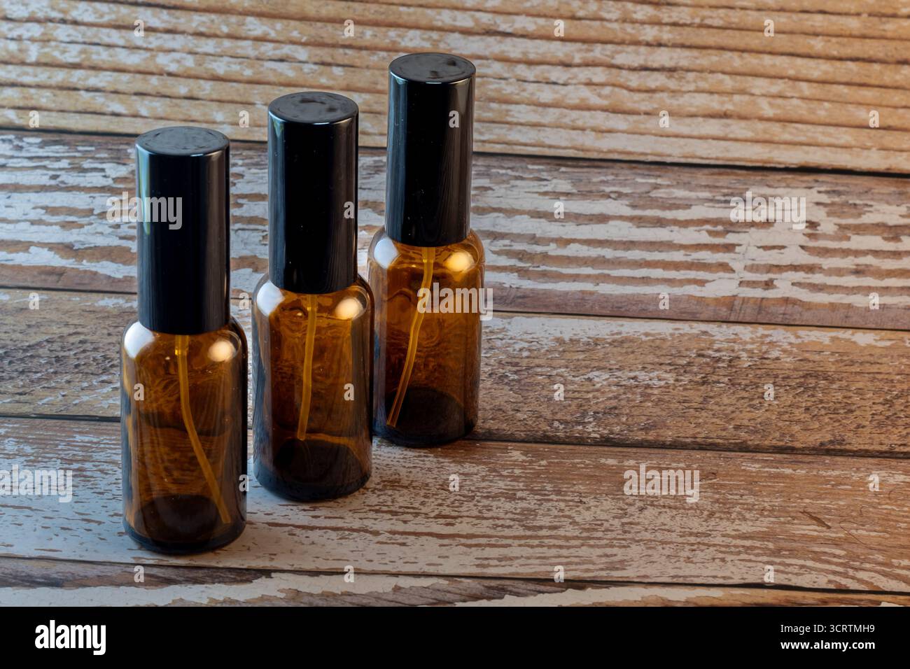 Drei bernsteinfarbene Sprühflasche auf Holzoberfläche Stockfoto