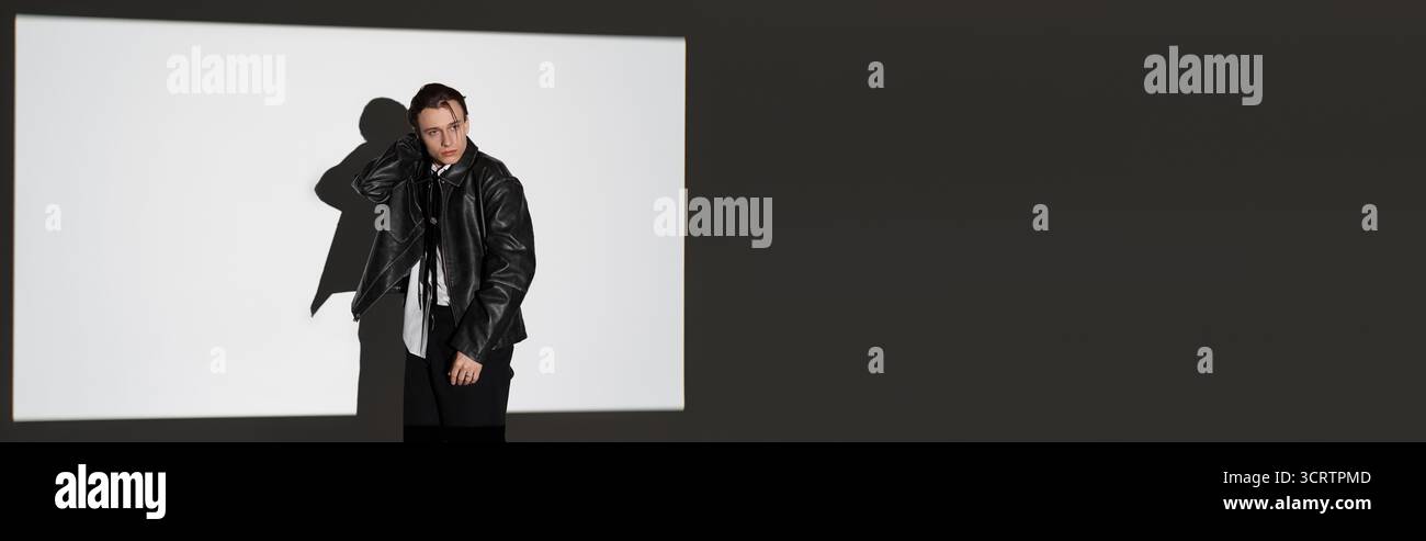 Ein gutaussehender Teenager steht selbstbewusst in einem stilvollen Outfit, das die moderne Jugendkultur annimmt. Stockfoto