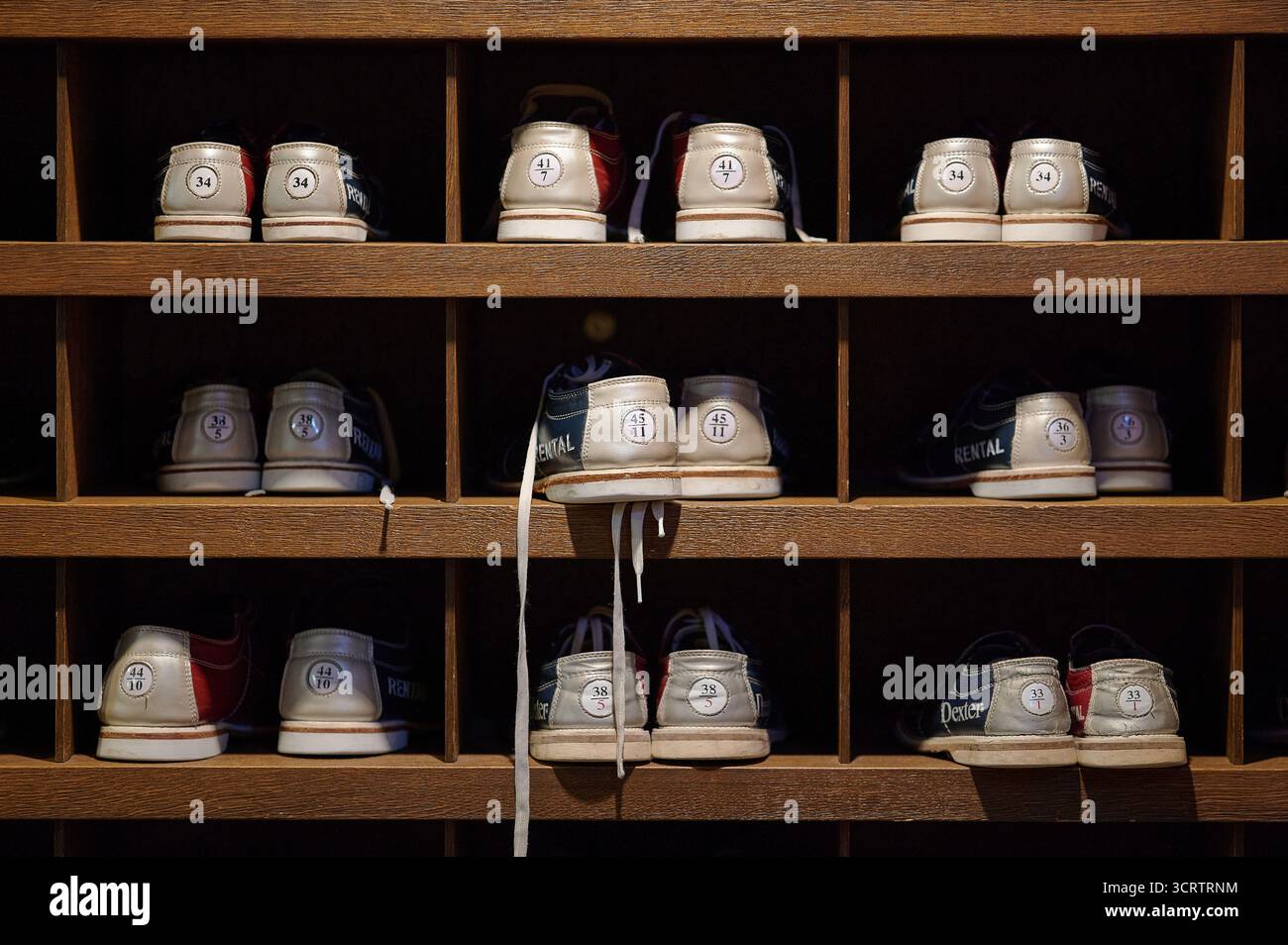 Vintage Bowlingverleih Schuhe organisiert in Holzregalen Gittermuster Innenbeleuchtung Sport Retro Schuhe Verleih Stockfoto