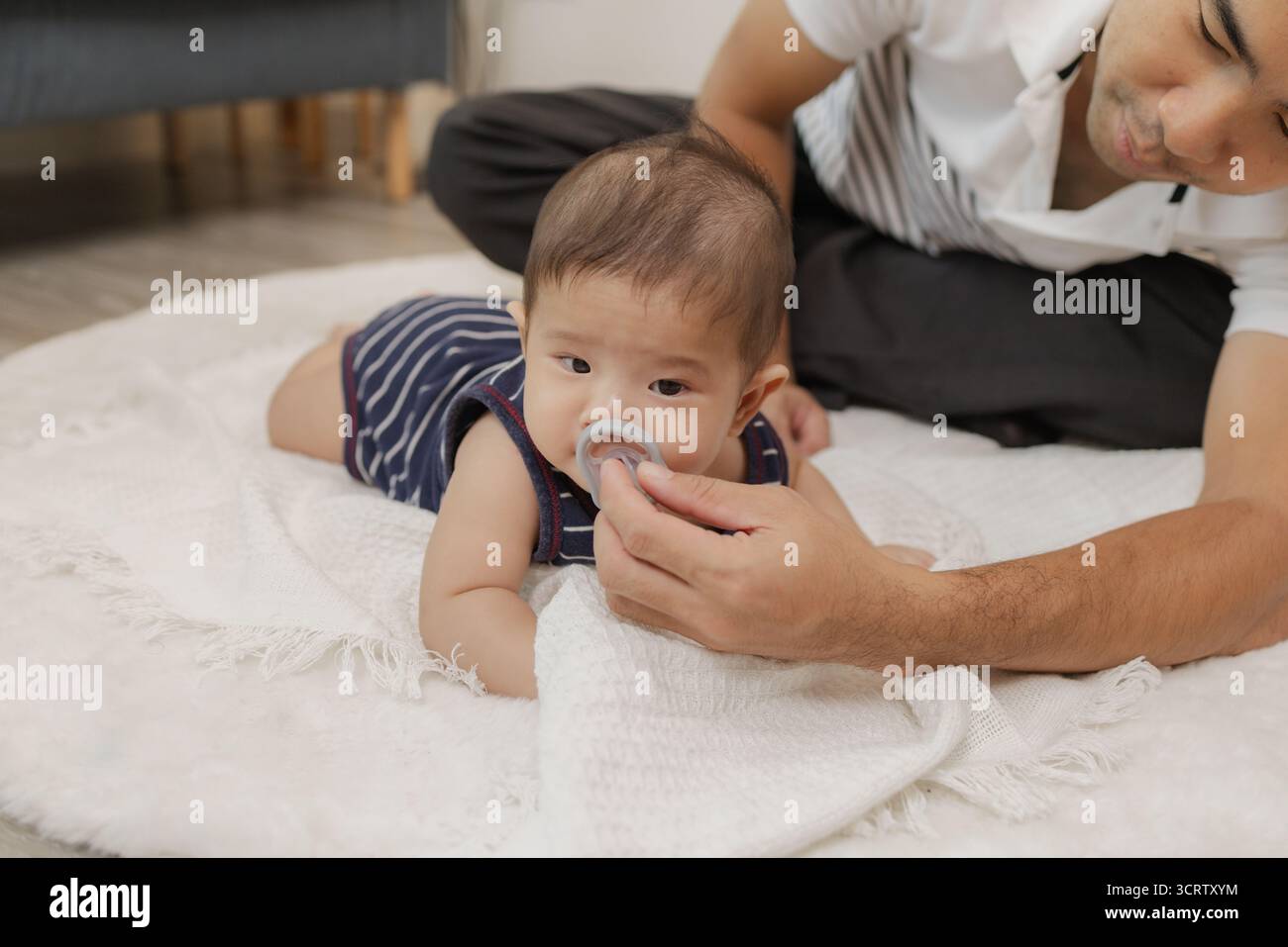 Ein Vater verbringt wertvolle Zeit mit seinem Baby, spielt und verbindet sich durch sanfte Pflege und lustige Momente auf einer weichen Matte. Das Baby erforscht die Bauchzeit und die Pa Stockfoto