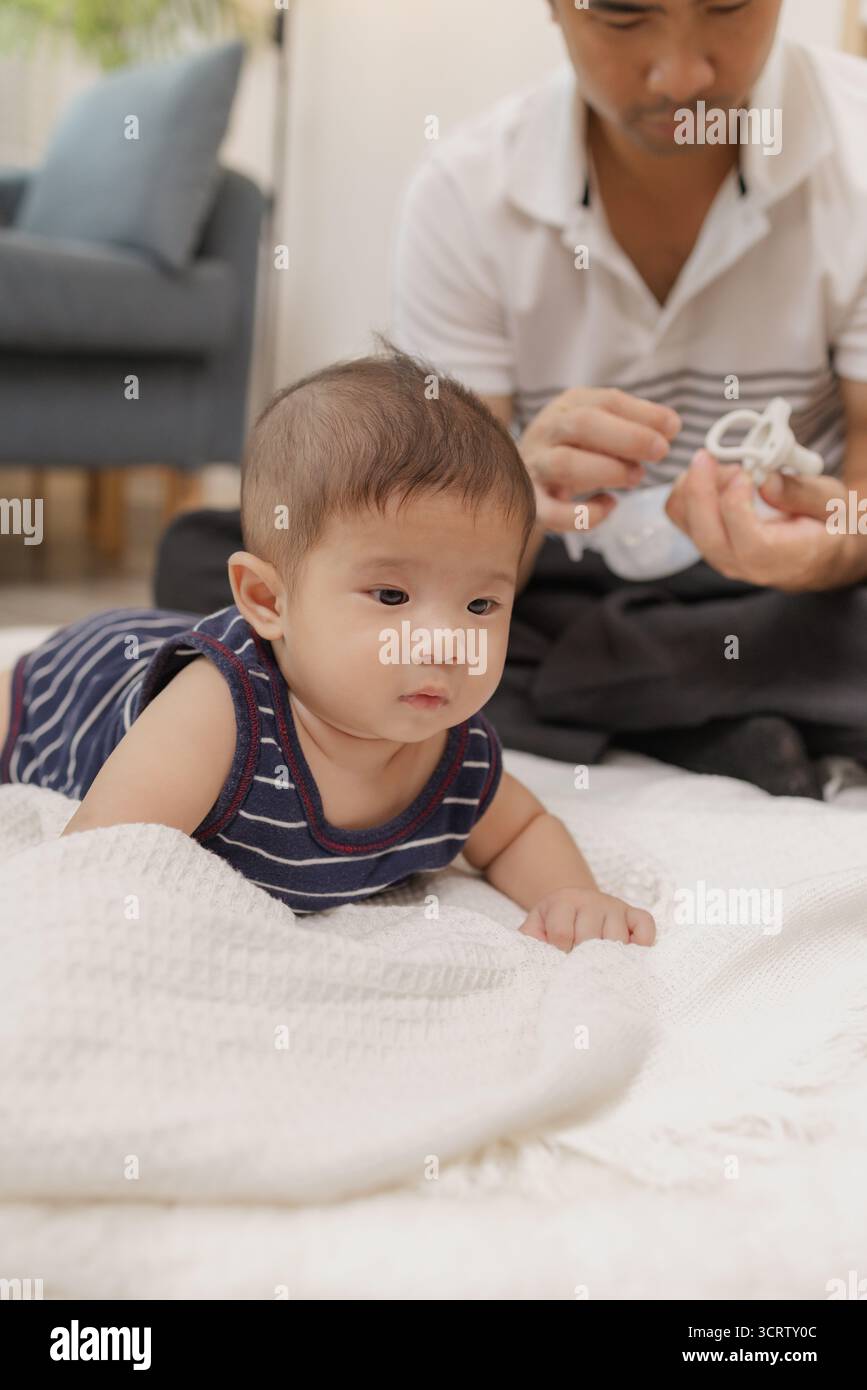 Ein Vater verbringt wertvolle Zeit mit seinem Baby, spielt und verbindet sich durch sanfte Pflege und lustige Momente auf einer weichen Matte. Das Baby erforscht die Bauchzeit und die Pa Stockfoto