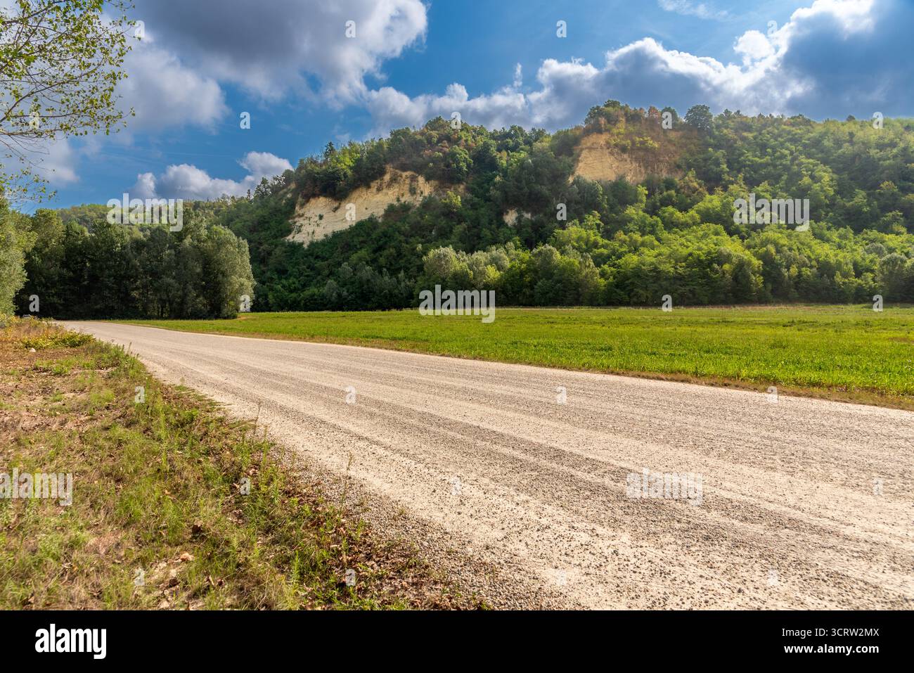 Sedimentäre Sandsteingesteine aus der geologischen Zeit des Piacenzischen Miozäns entlang des Tanaro mit Feldweg in der Region Langhe, Piemont, Italien Stockfoto
