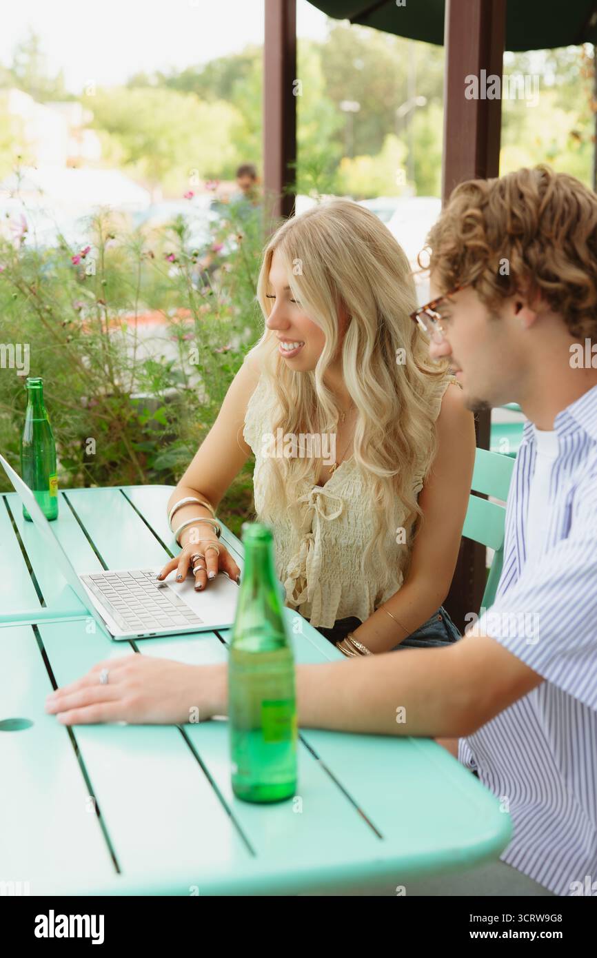 Ein Paar, das am Laptop an einem Café-Tisch im Freien arbeitet Stockfoto