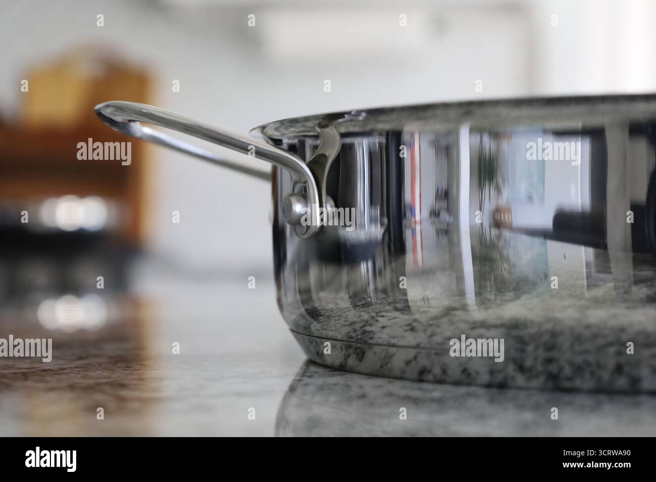 Edelstahlpfanne mit Griff auf Granitküche Stockfoto