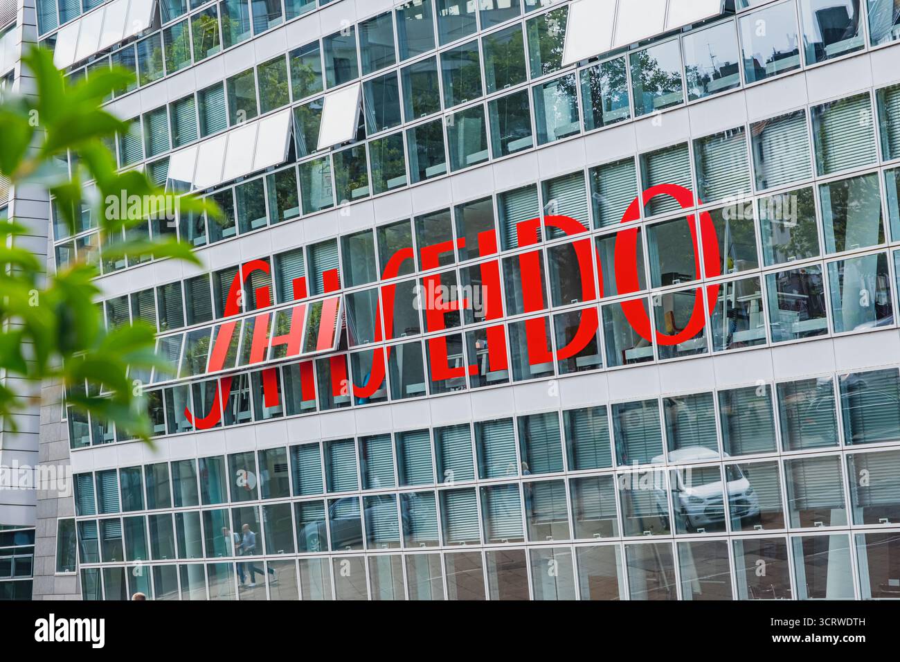 Großes rotes Shiseido-Logo auf reflektierenden Fenstern eines modernen Büroglasgebäudes im Düsseldorfer Stadtteil Medienhafen Stockfoto