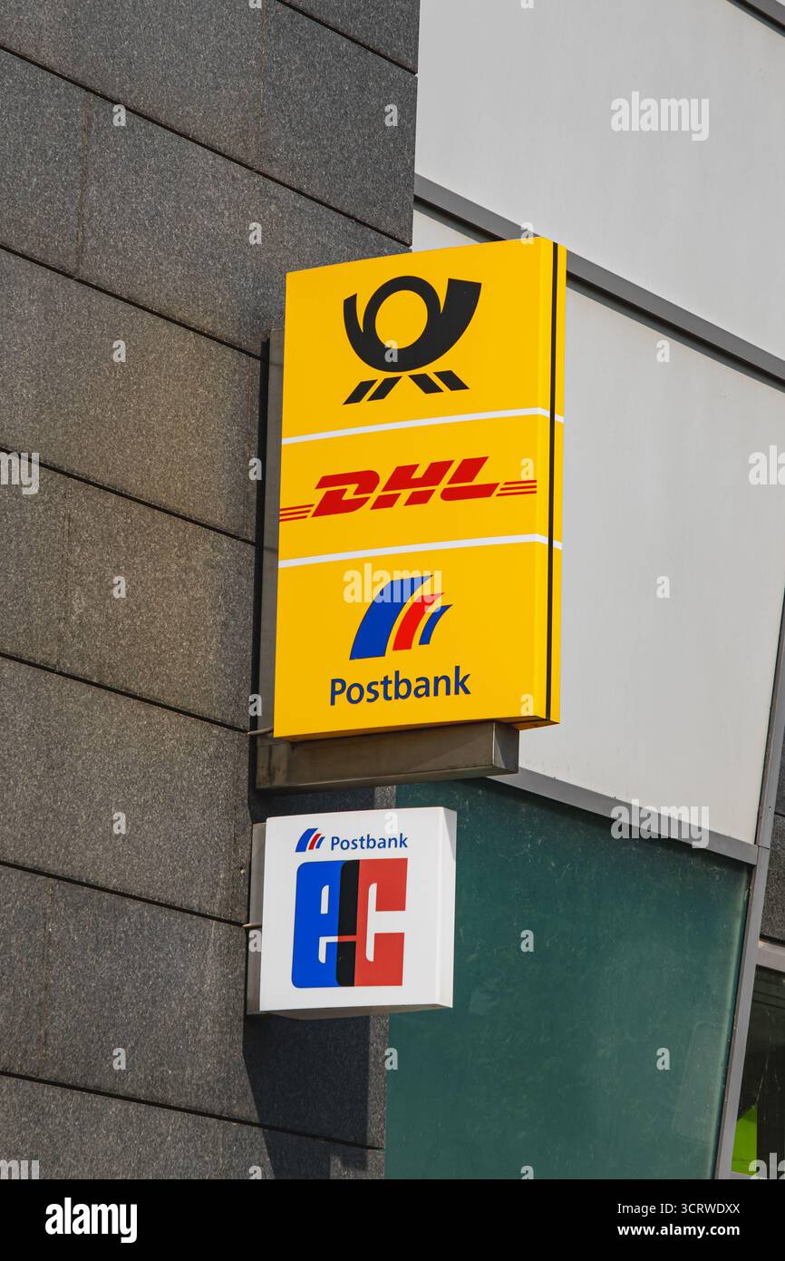 Schilder von DHL, Postbank und EC Card vor einem modernen Gebäude Stockfoto