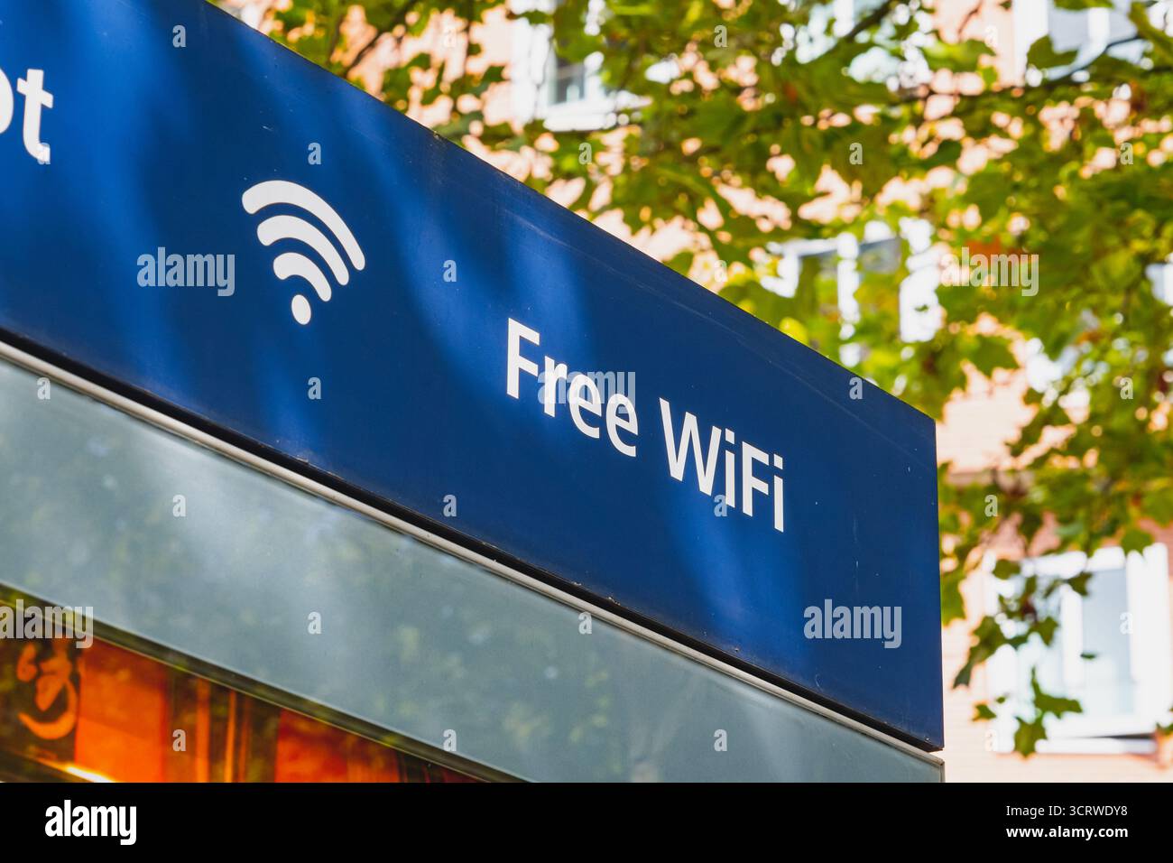 Ein blaues „kostenloses WLAN“-Schild mit einem WLAN-Symbol an Bäumen und Gebäuden Stockfoto