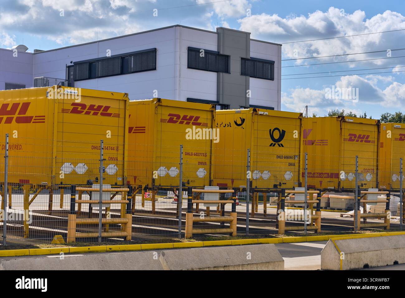Winsen, Deutschland; 30. September 2025: Reihe von DHL-Logistikcontainern, die am Standort des Amazon-Vertriebszentrums geparkt werden, symbolisieren die globale Paketzustellung, e Stockfoto