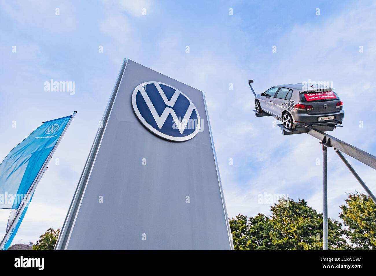 Logo des Volkswagen Automobilherstellers auf einem Händlerstand mit hängendem Fahrzeug und Flagge daneben Stockfoto