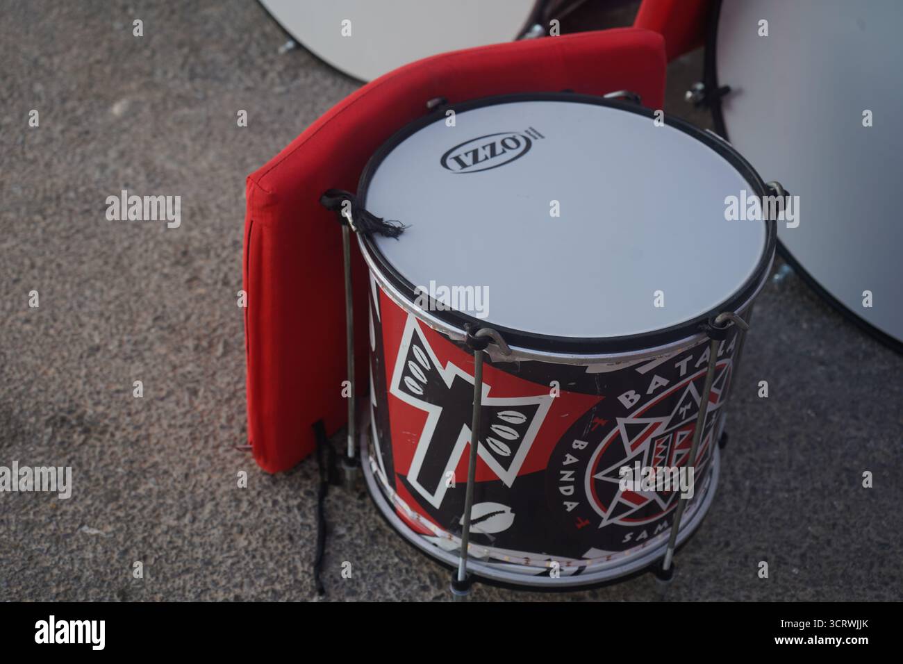 Nahaufnahme einer „Batala Banda Samba Reggae“-Trommel mit markantem Rot-, Schwarz- und weiß-Design, die während des 3. Malevizi Festivals auf dem Boden ruht. Stockfoto