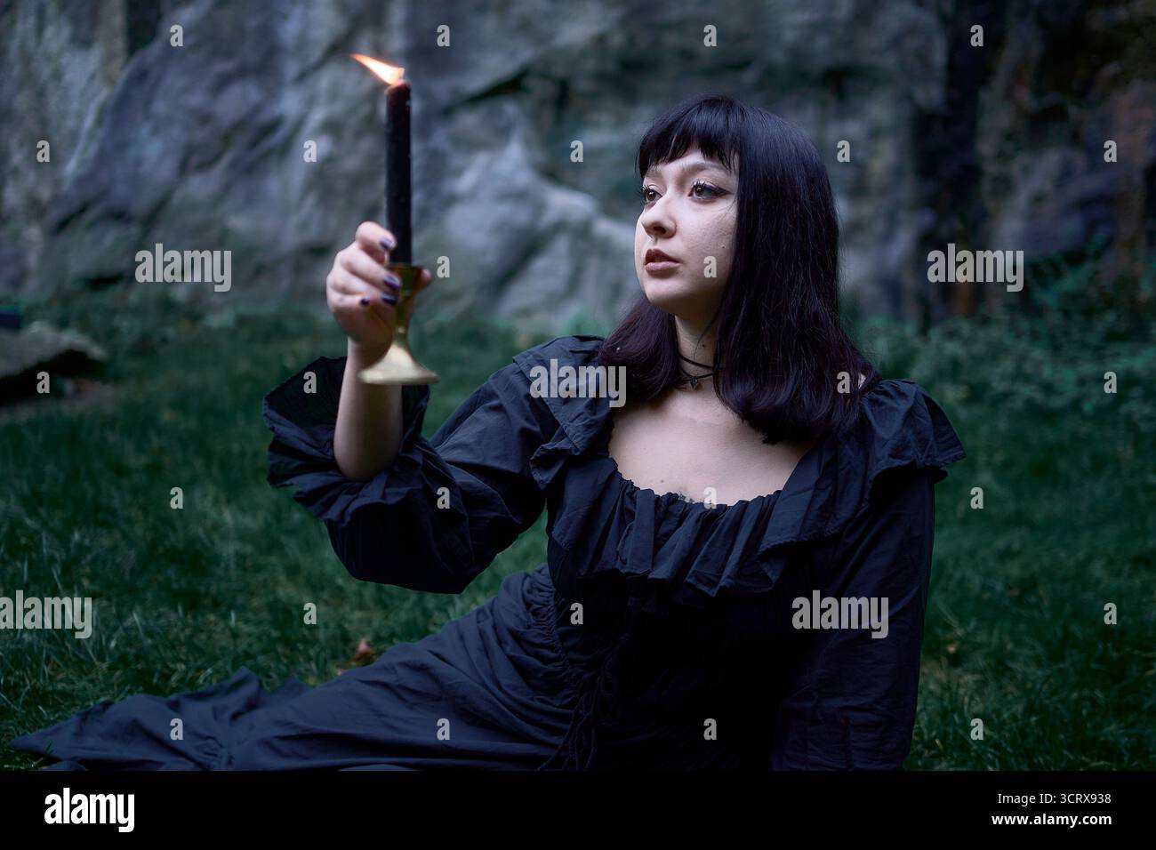 Zwei Frauen in langen schwarzen Kleidern sitzen an Halloween auf schwarzen Felsen, lesen Tarotkarten, führen ein Hexenritual durch, moderne Hexe Stockfoto