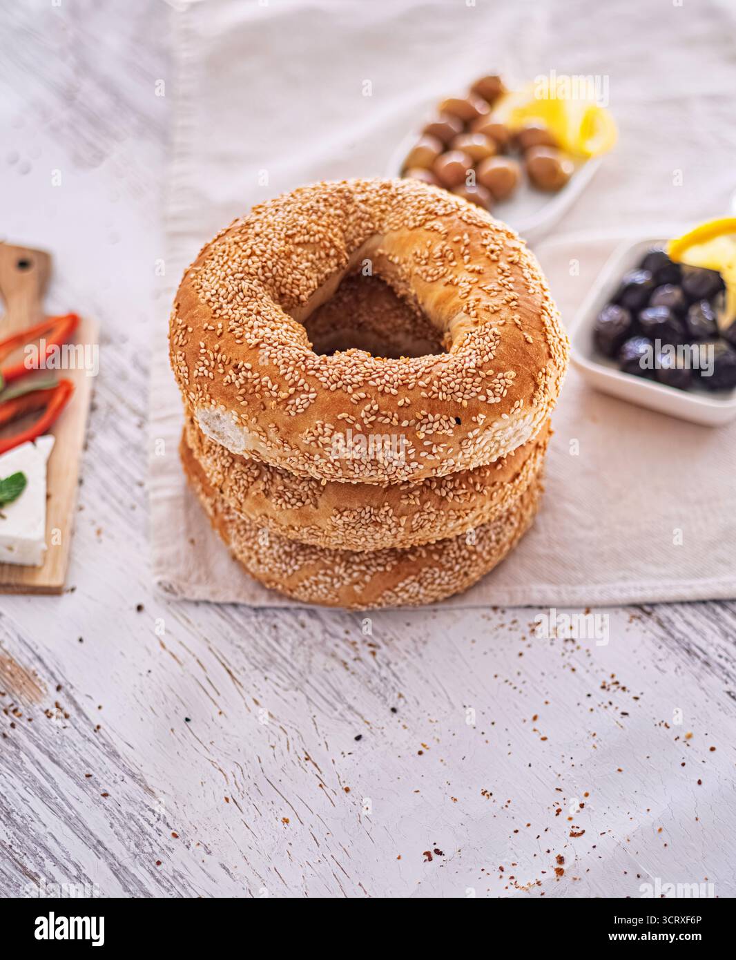 Ein Stapel von drei Simiten mit Sesamkruste (türkische Bagels) wird auf ein weiches beiges Tuch gelegt. Das traditionelle türkische Frühstück. Selektiver Fokus. Stockfoto
