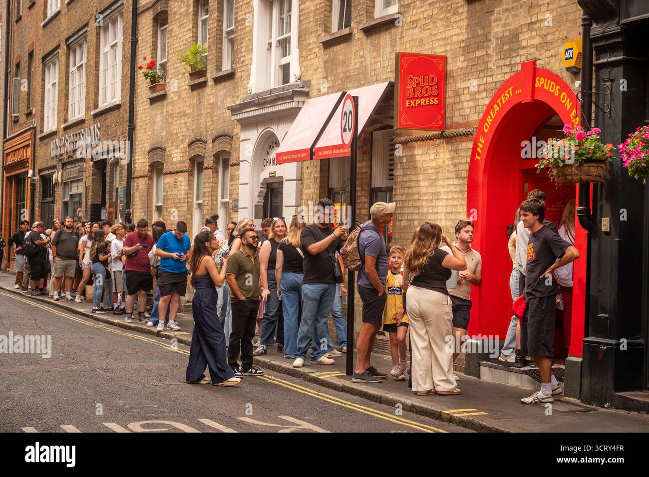 LONDON – 23. AUGUST 2025: Lange Warteschlangen für Spudbros Express – Kartoffelverkaufsstelle in der Archer Street in Soho, West End Stockfoto