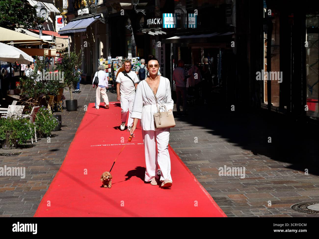 Gut gekleidete Dame, die mit ihrem Hund auf dem roten Teppich in Baden-Baden, einem Kurort im Bundesland Baden-Württemberg, im Südwesten Deutschlands, unterwegs ist Stockfoto